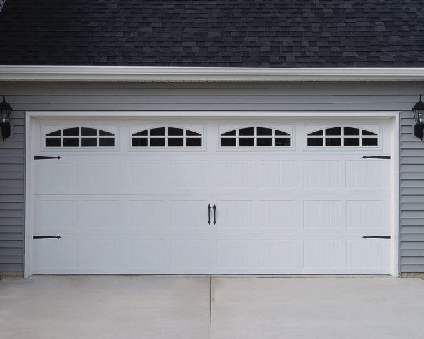 White paneled garage door with arched window inserts on a gray house